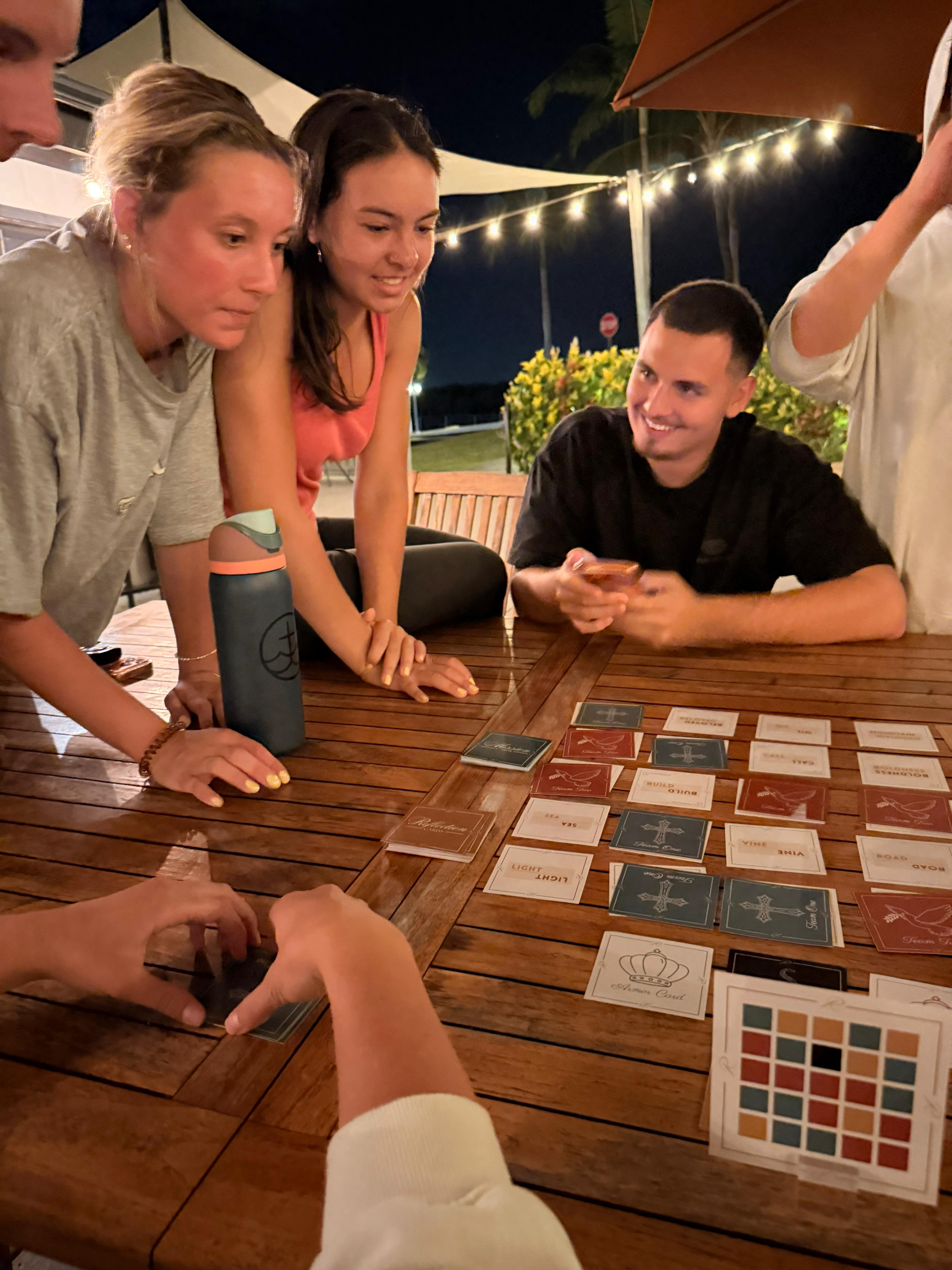 Friends playing Revival outdoors under string lights at night
